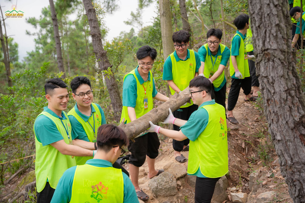 Mỗi bạn một tay, phối hợp nhịp nhàng để di chuyển cây gỗ đến điểm tập kết