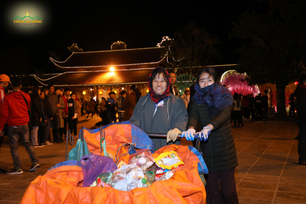Chị Trần Ngọc Oanh (bên trái) đang đi thu gom rác trong khuôn viên chùa