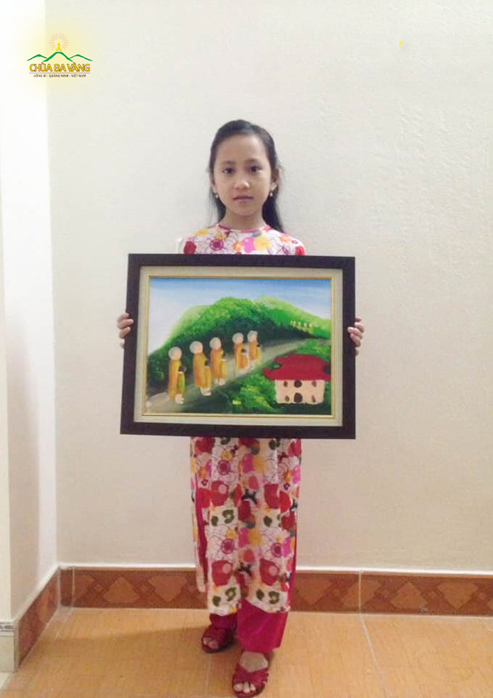 Bé Hoàng Tuyết Mai Chi chụp hình cùng với bức tranh chư Tăng khất thực trong rừng thiền