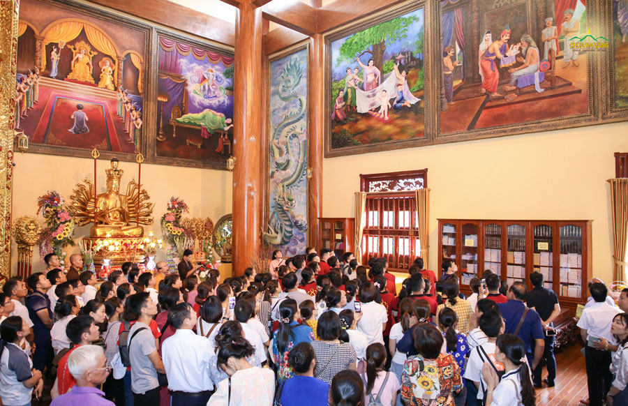 Các thành viên trong Công ty bảo hiểm AIA chi nhánh miền Bắc lắng nghe quý Thầy giới thiệu về cuộc đời Đức Phật qua 37 bức tranh tại chính điện chùa Ba Vàng