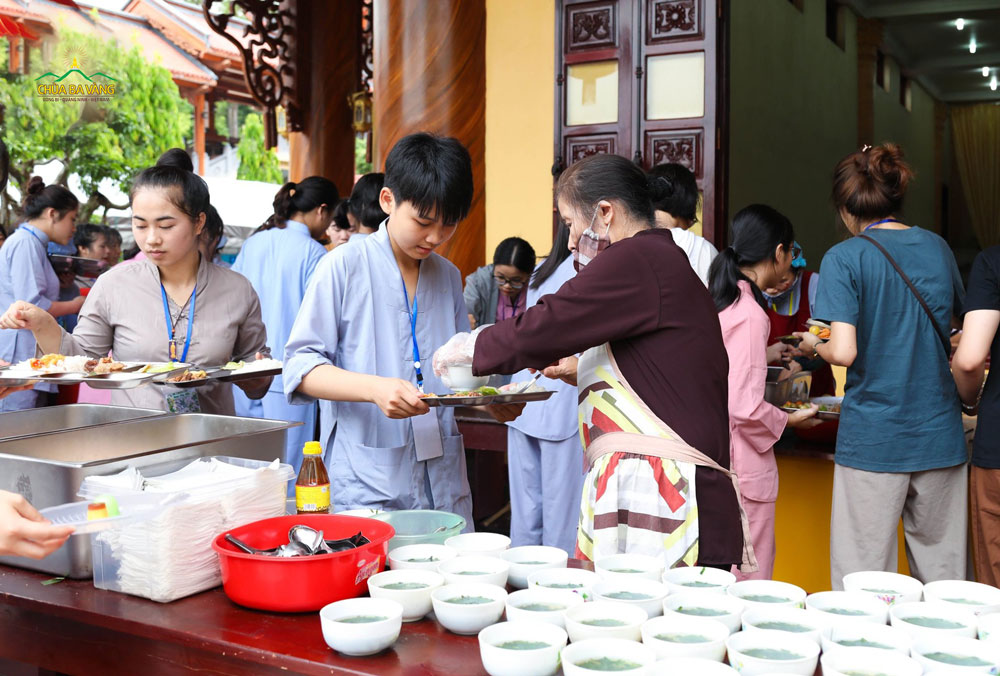 Các Phật tử ban hành đường sắp xếp đồ ăn lên khay cơm cho các bạn trong các bữa ăn