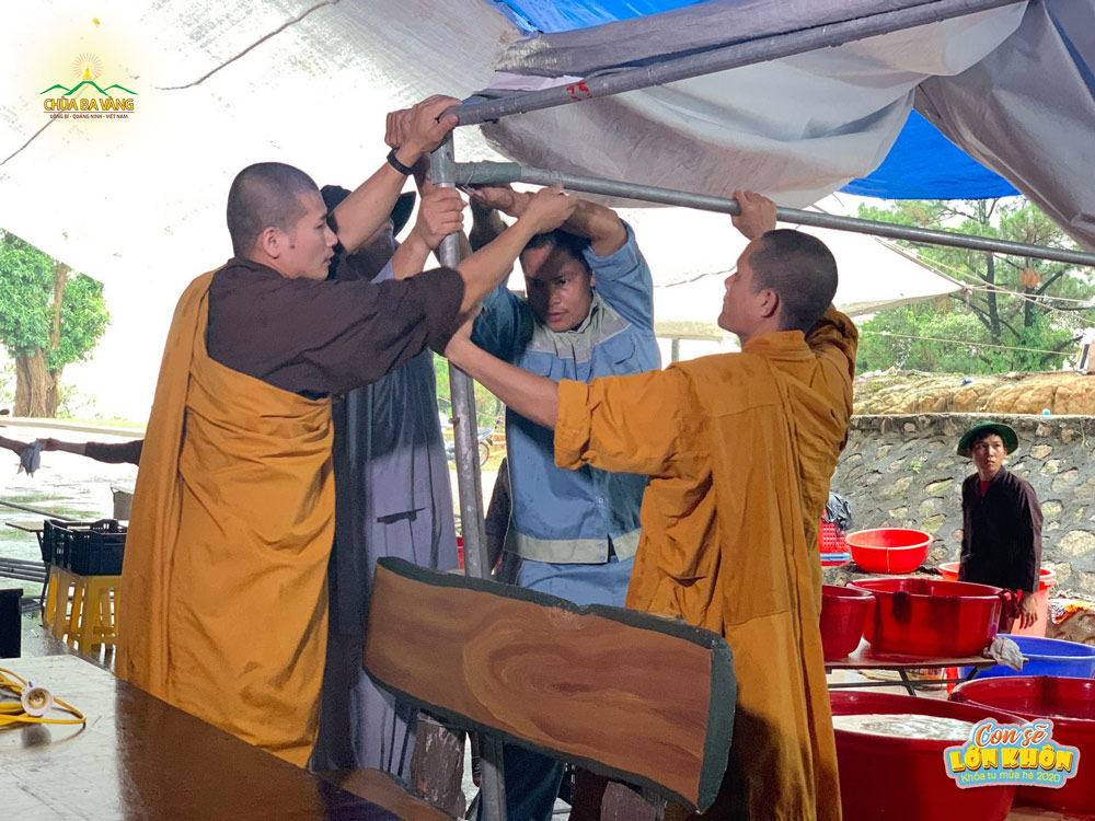 Quý Thầy hỗ trợ Phật tử cột lại bạt che mưa nơi rửa bát của các bạn khóa sinh