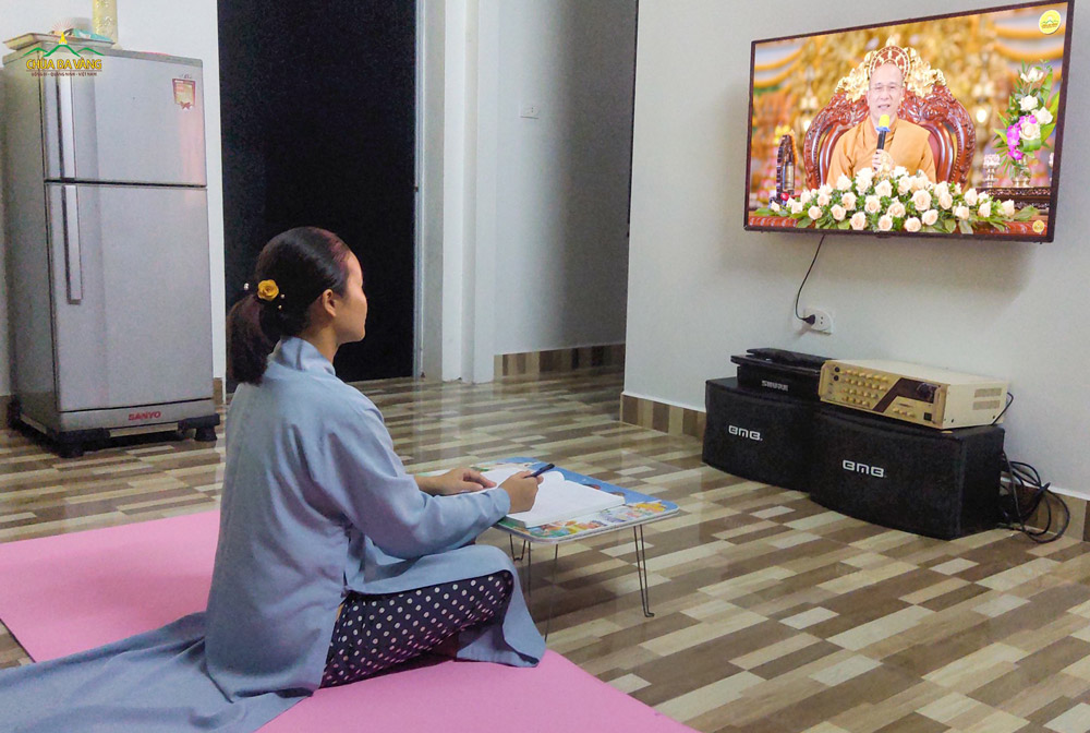 Cô Phật tử chăm chú lắng nghe và ghi lại ý nghĩa của bài kinh Tam Bảo