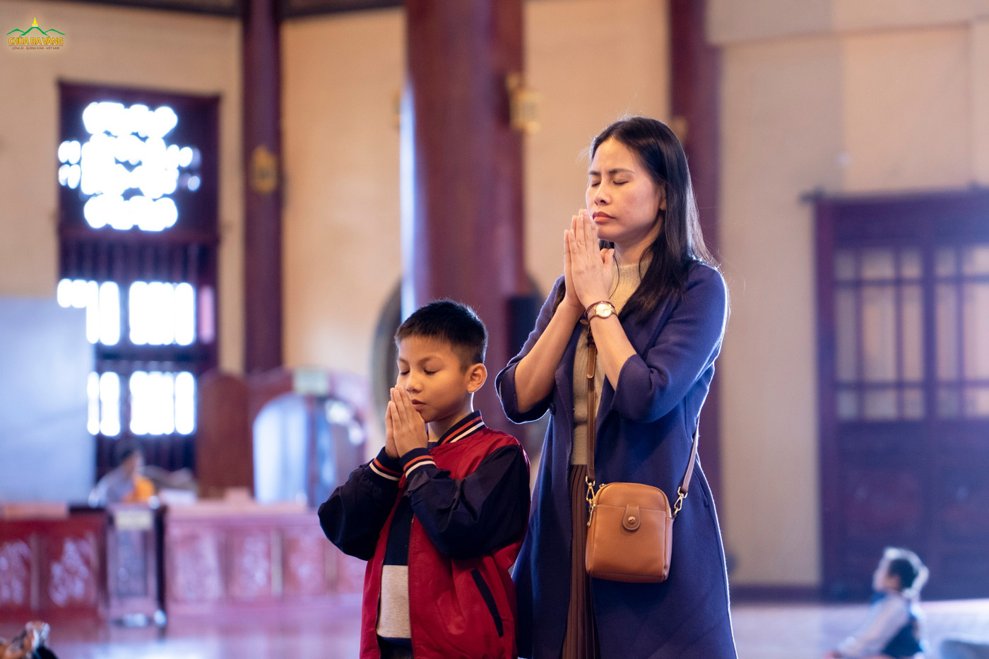 Hai mẹ con mình cùng cầu nguyện trước ngôi Tam Bảo