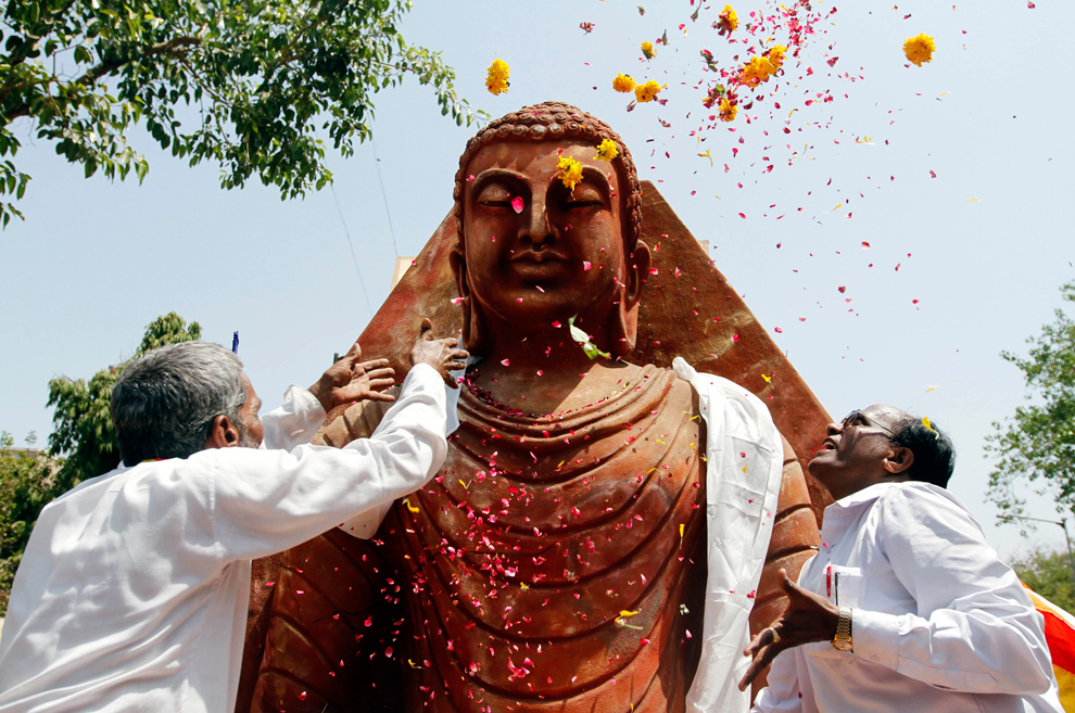 Hai Phật tử người Ấn Độ tung những cánh hoa lên bức tượng Đức Phật trong dịp Lễ Phật Đản ở thành phố Ahmedabad, 17/05/2011 (Nguồn: Internet) 