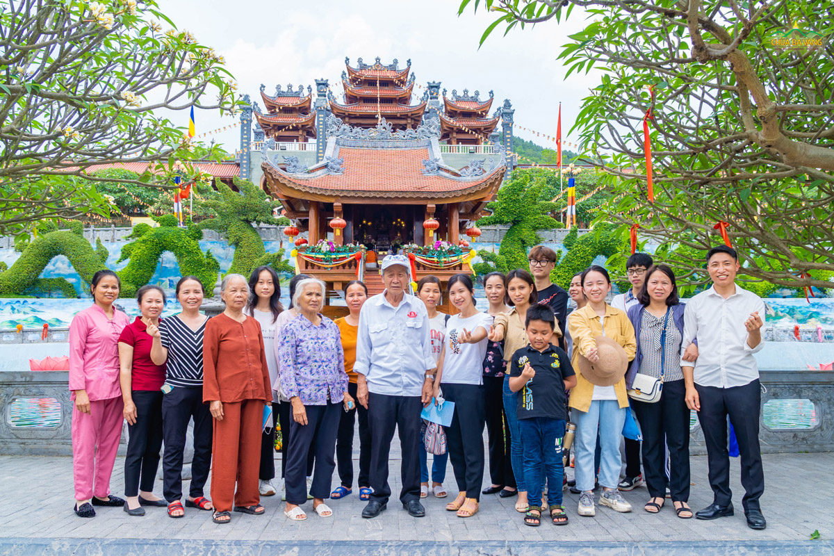 Đoàn du khách vui vẻ chụp ảnh lưu niệm trước chùa Một Cột trong khuôn viên thiền môn Ba Vàng