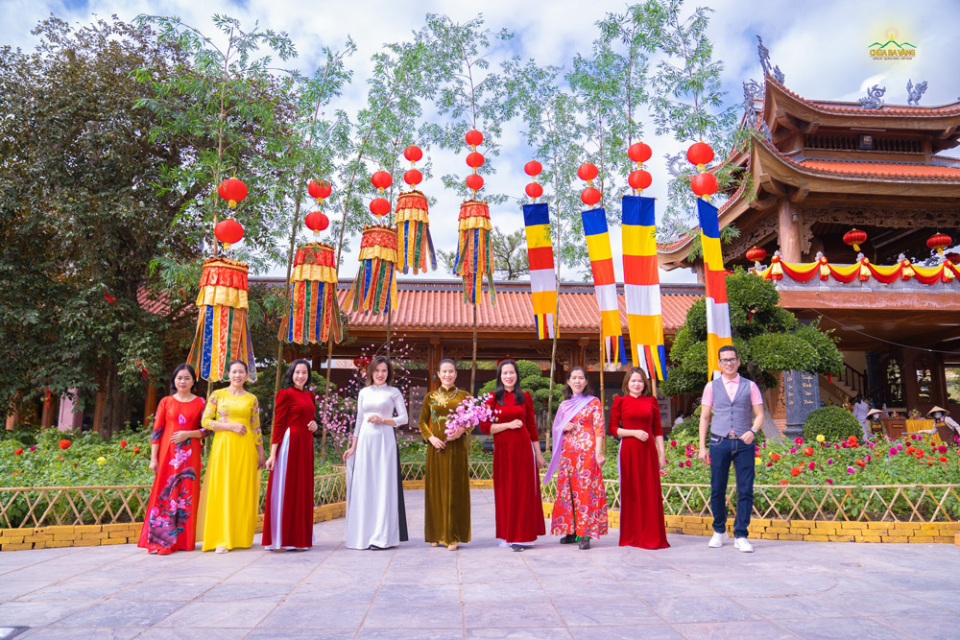 Trong những chiếc áo dài rực rỡ, các Phật tử đã cùng nhau lưu lại hình ảnh đẹp bên tiểu cảnh cây nêu với lá cờ Phật giáo cùng những tấm phướn  