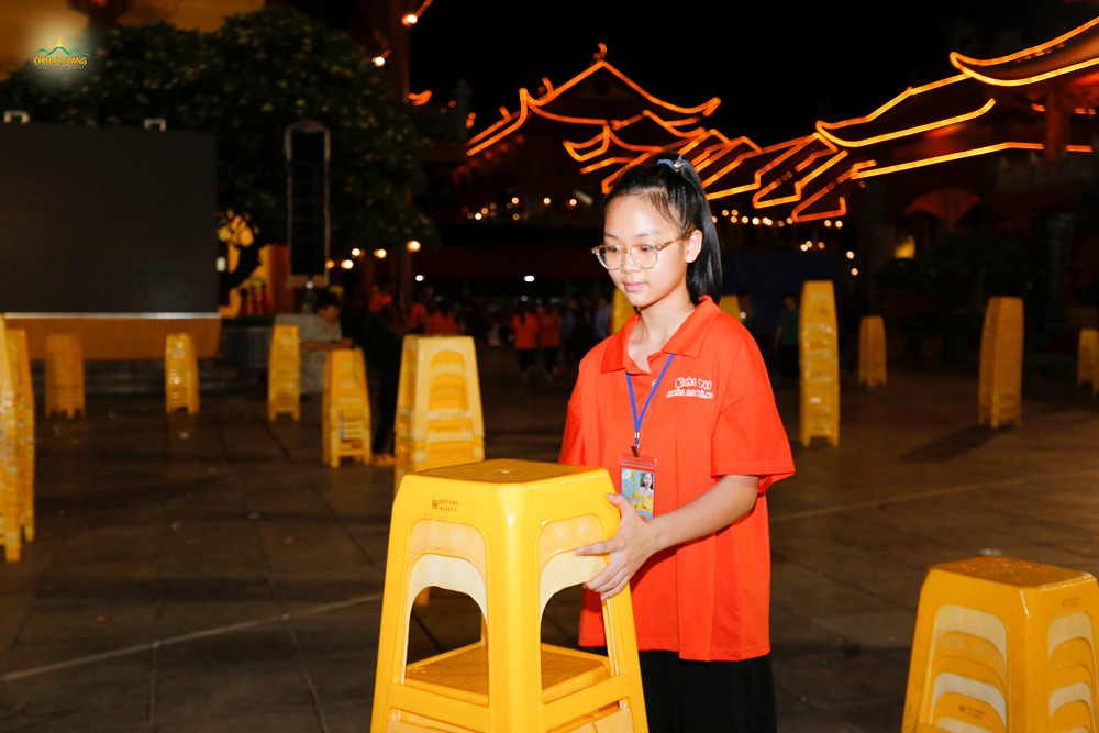 Khánh Linh hỗ trợ các cô bác Phật tử xếp ghế sau chương trình